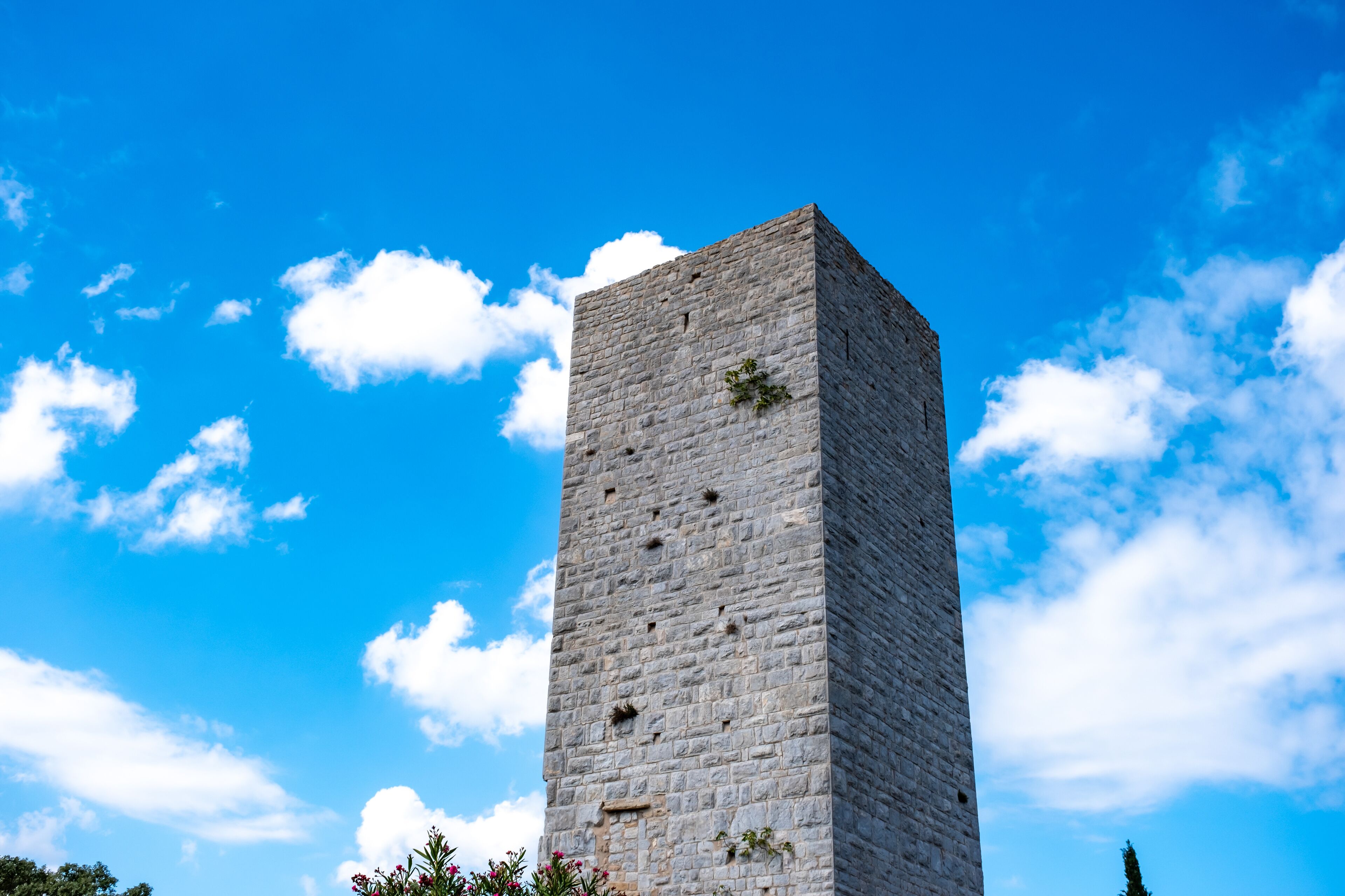 A tall stone tower against a blue sky with clouds.