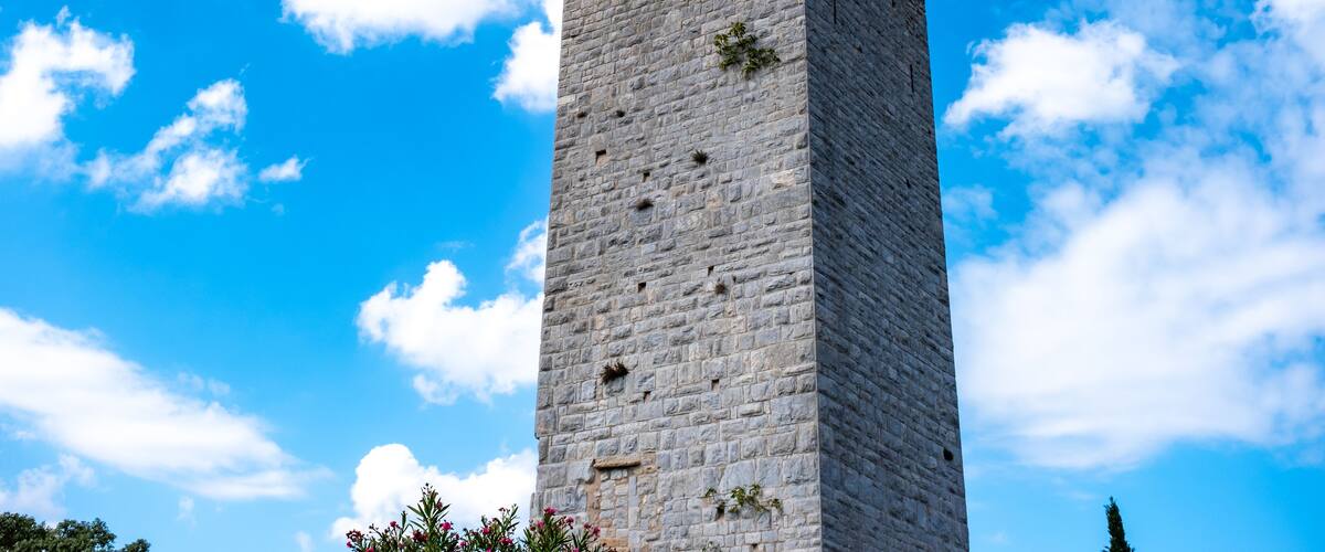 A tall stone tower against a blue sky with clouds.