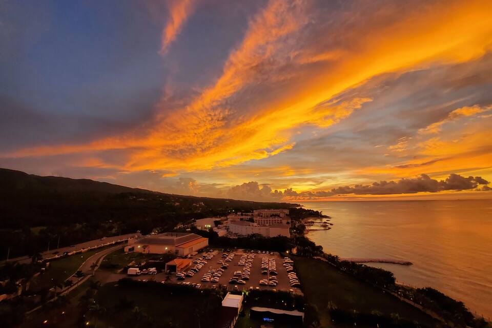 A sunset over a coastal city with a parking lot and buildings.