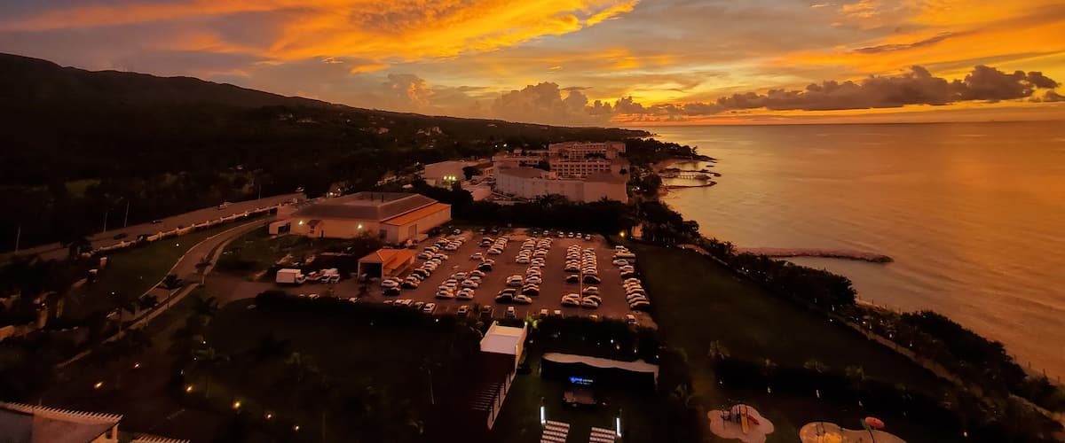 A sunset over a coastal city with a parking lot and buildings.