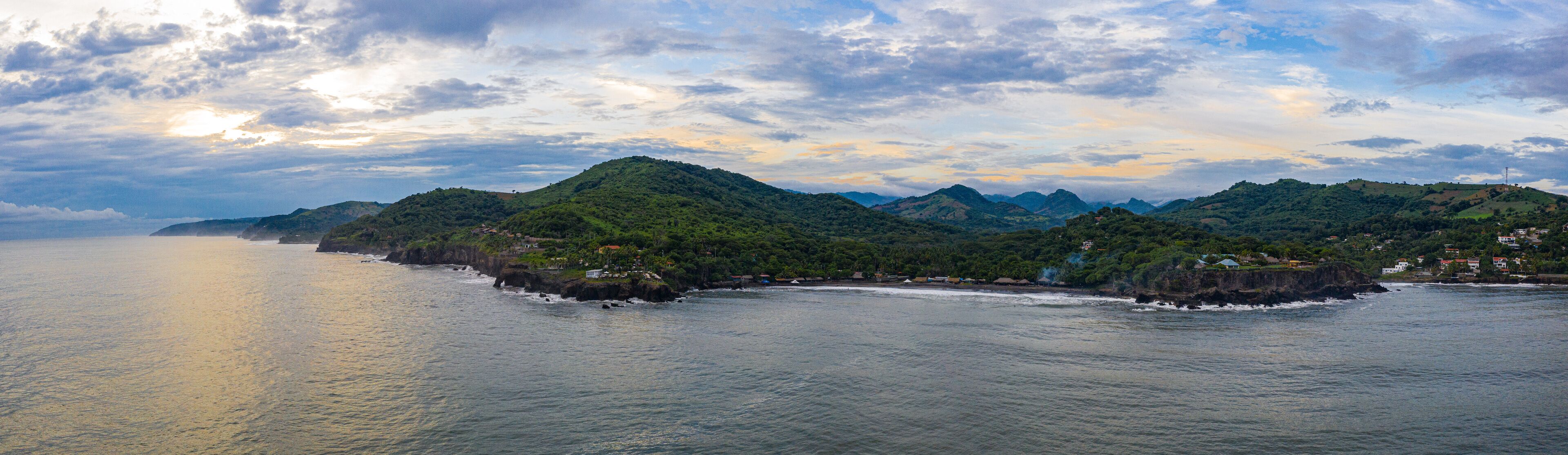 A coastal landscape with green hills and a calm sea.