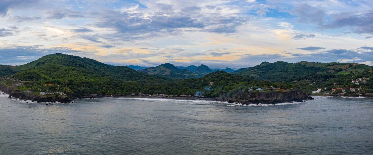 A coastal landscape with green hills and a calm sea.