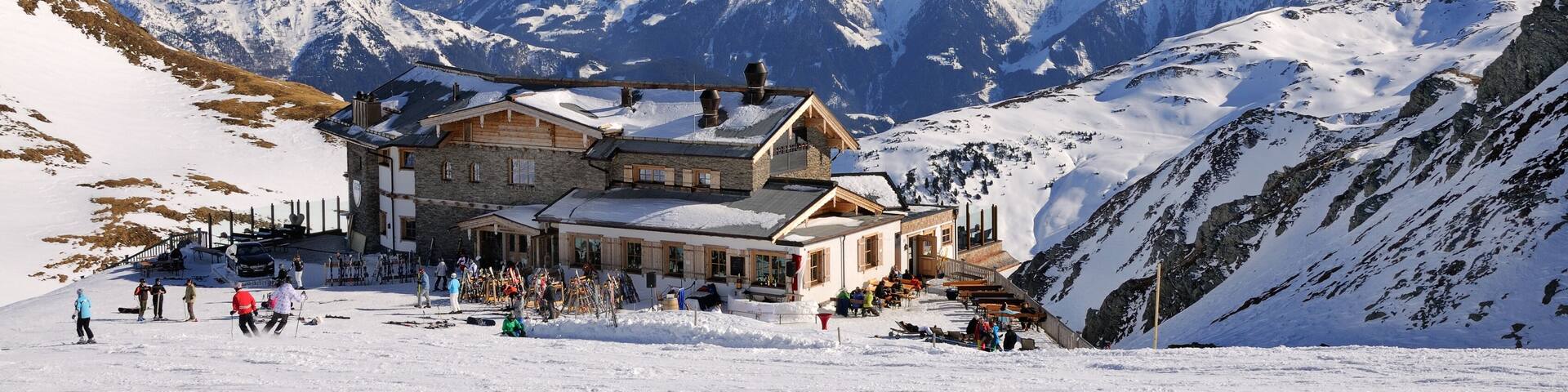 A snow-covered mountain with a lodge and skiers.