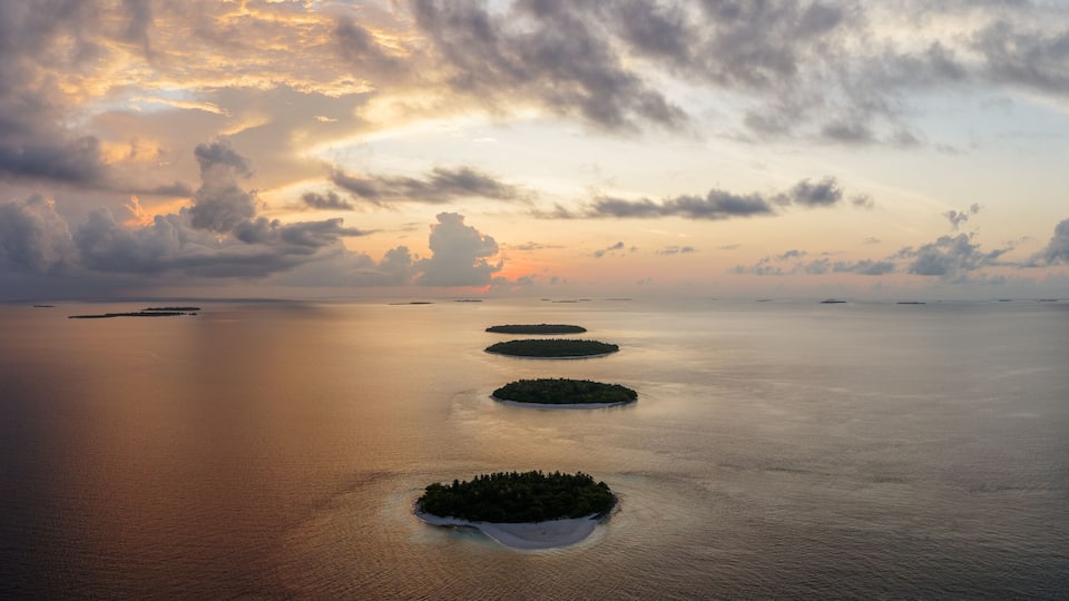 A calm sea with four small islands aligned in a row.
