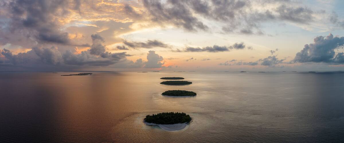 A calm sea with four small islands aligned in a row.