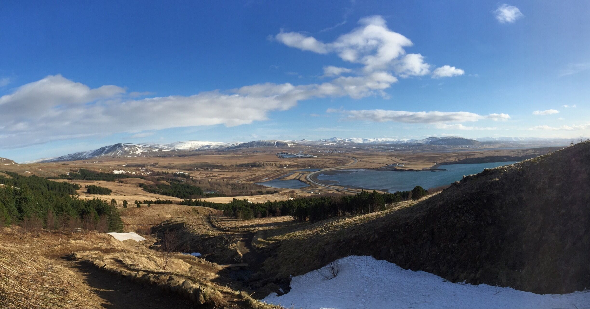 A mountainous landscape with a lake, snow-capped peaks, and a clear sky.