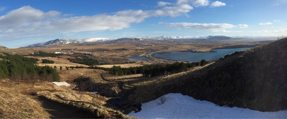 A mountainous landscape with a lake, snow-capped peaks, and a clear sky.
