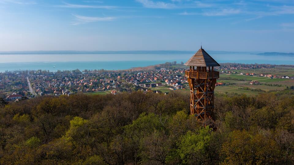 A wooden observation tower overlooking a coastal town and a lake.