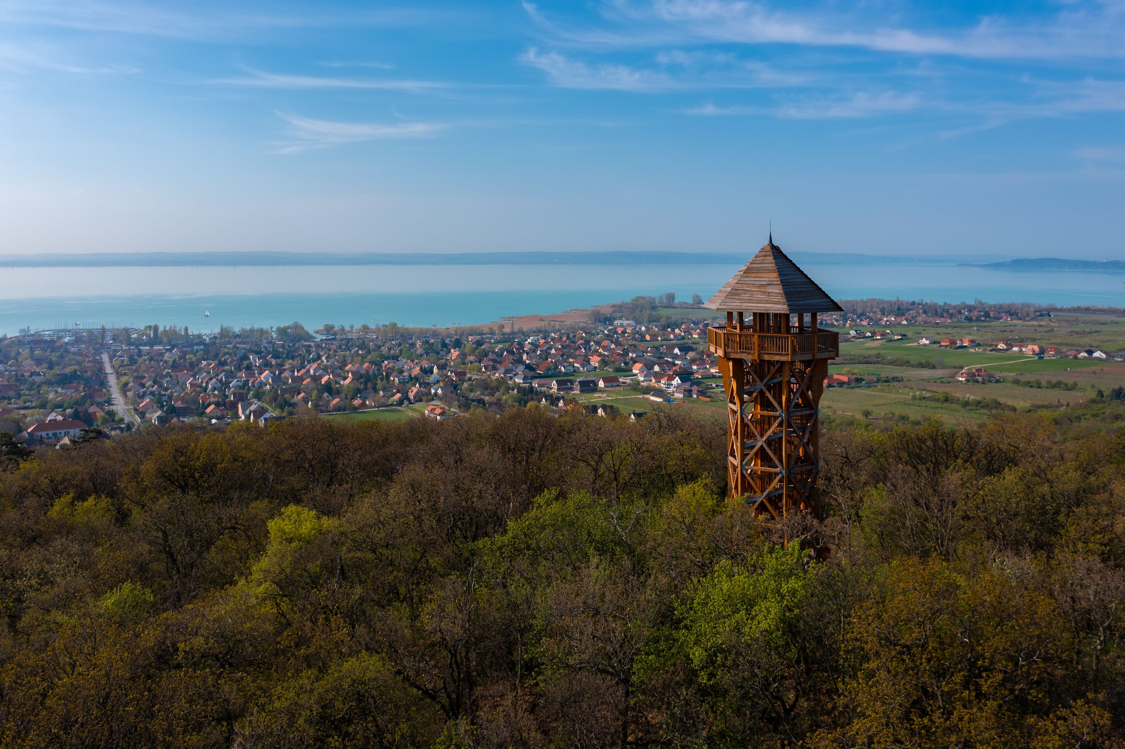 A wooden observation tower overlooking a coastal town and a lake.