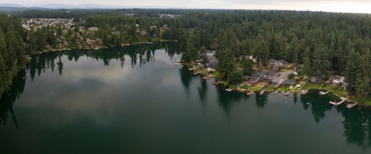 A lake surrounded by dense forests and residential areas.
