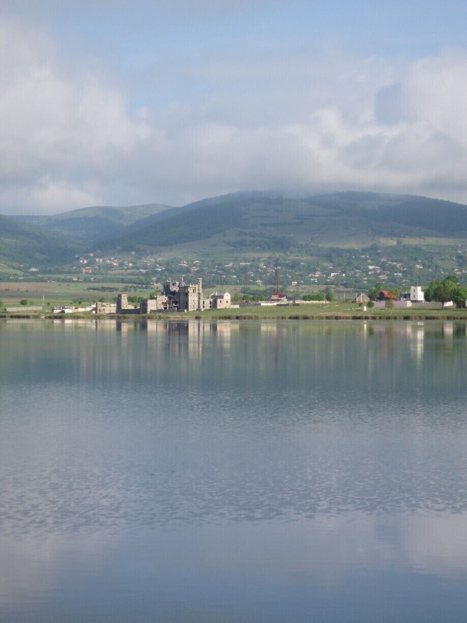 View from a lake in the country of Georgia.  This picture is looking out over a body of water called Bazaleti Lake.  Out on the shore of the lake, it looks as if someone is constructing a building that looks like a small castle.  