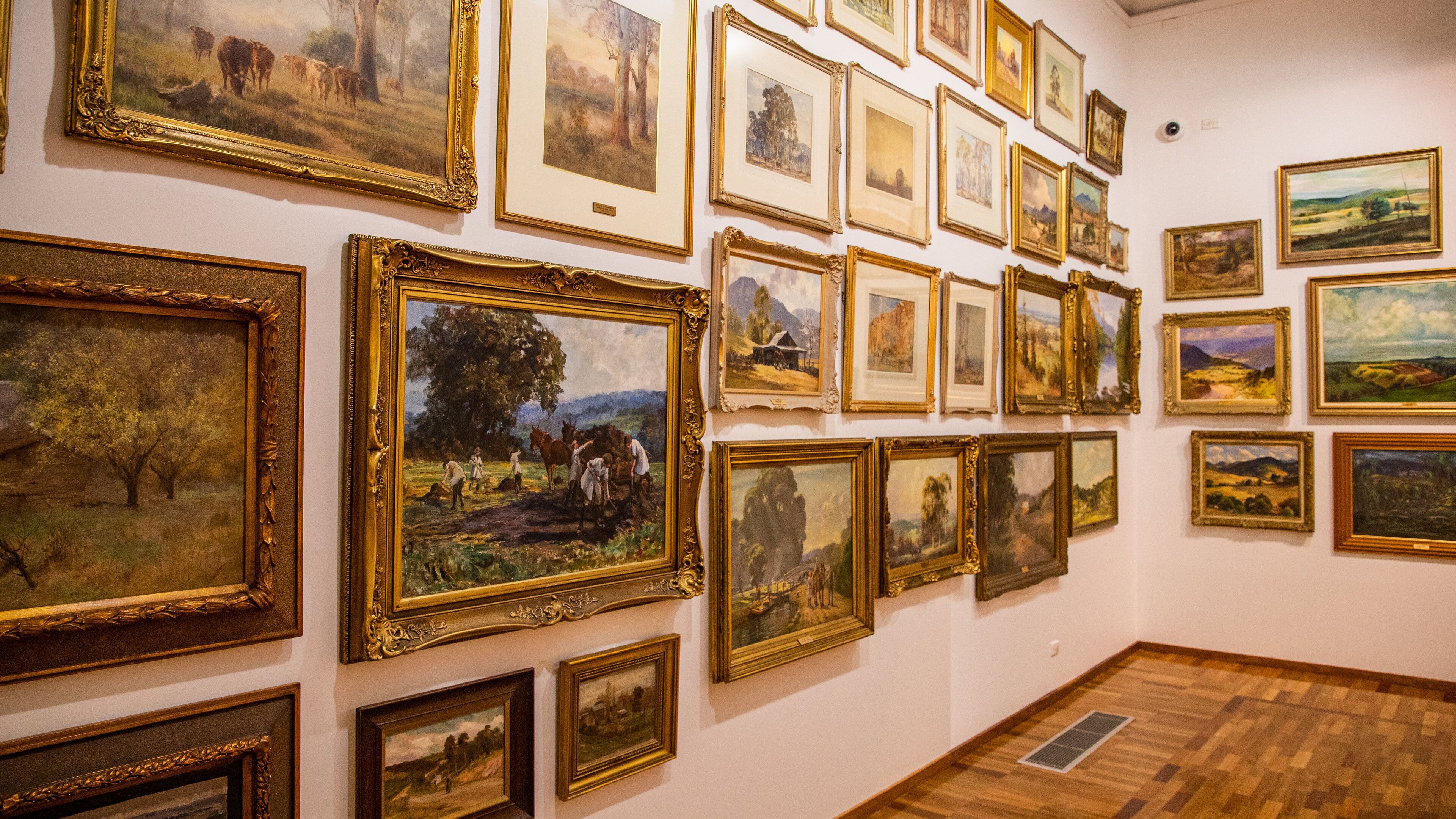 Eine Galerie mit verschiedenen gerahmten Landschaftsbildern an den Wänden.