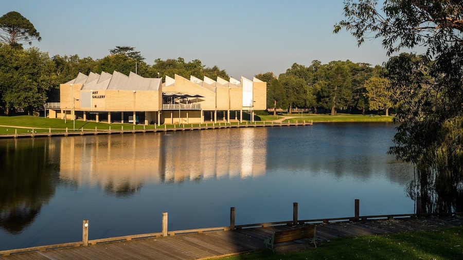 Une galerie d’art contemporain située au bord d’un lac paisible, avec une jetée en bois.