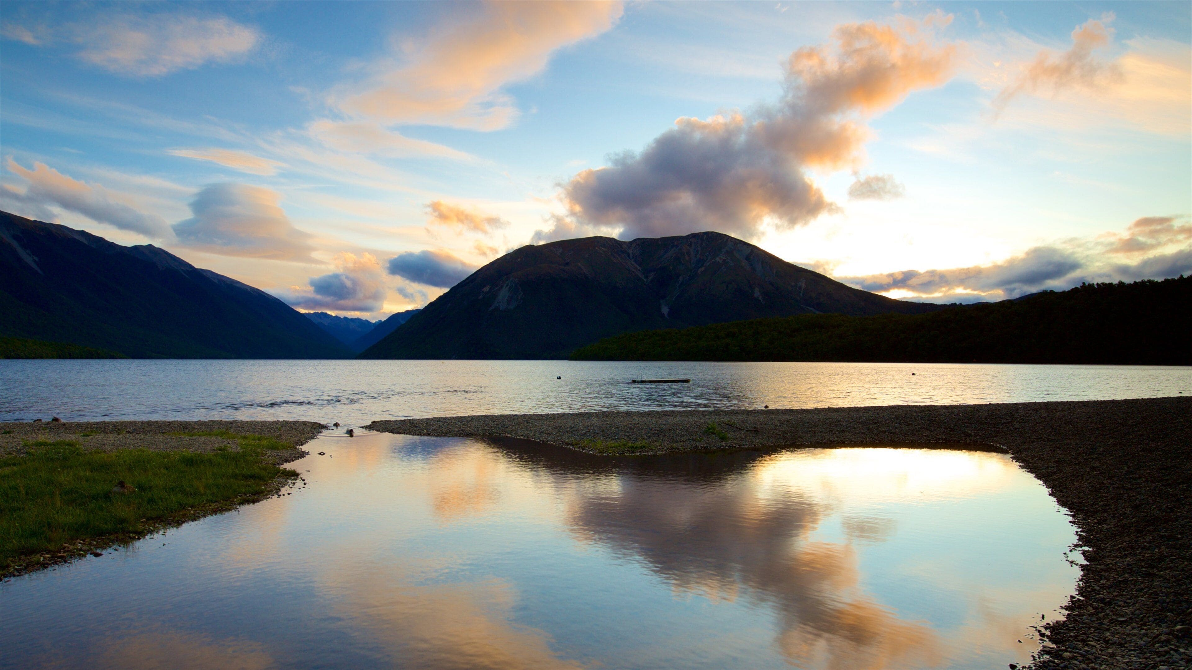 A calm lake with mountains in the background and a clear sky.
