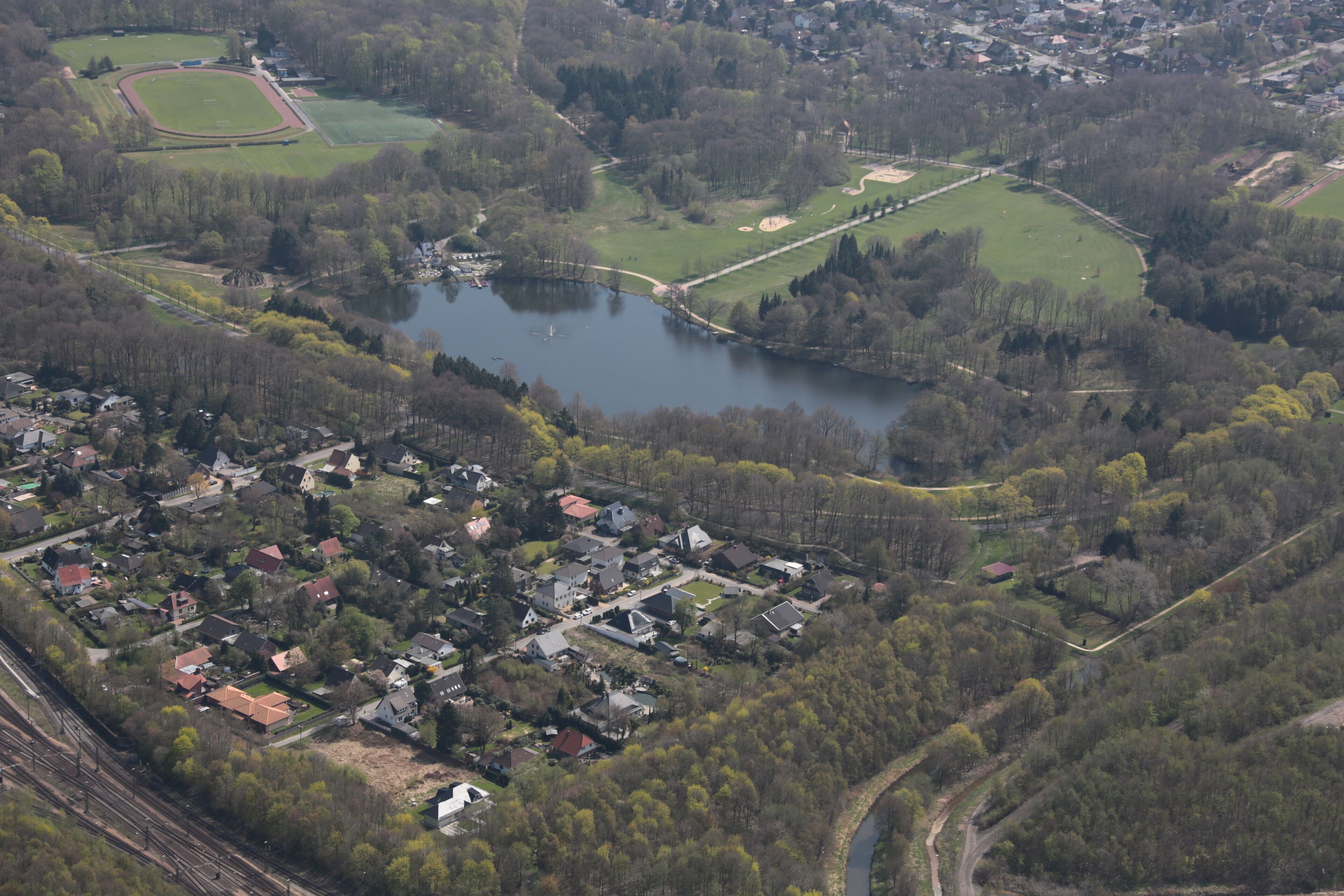 An aerial view of a town with a lake, surrounded by greenery and residential areas.