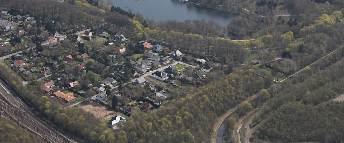 An aerial view of a town with a lake, surrounded by greenery and residential areas.