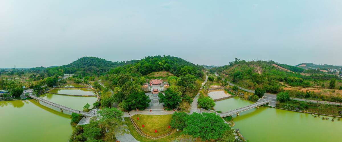 A traditional temple surrounded by water bodies and lush greenery.