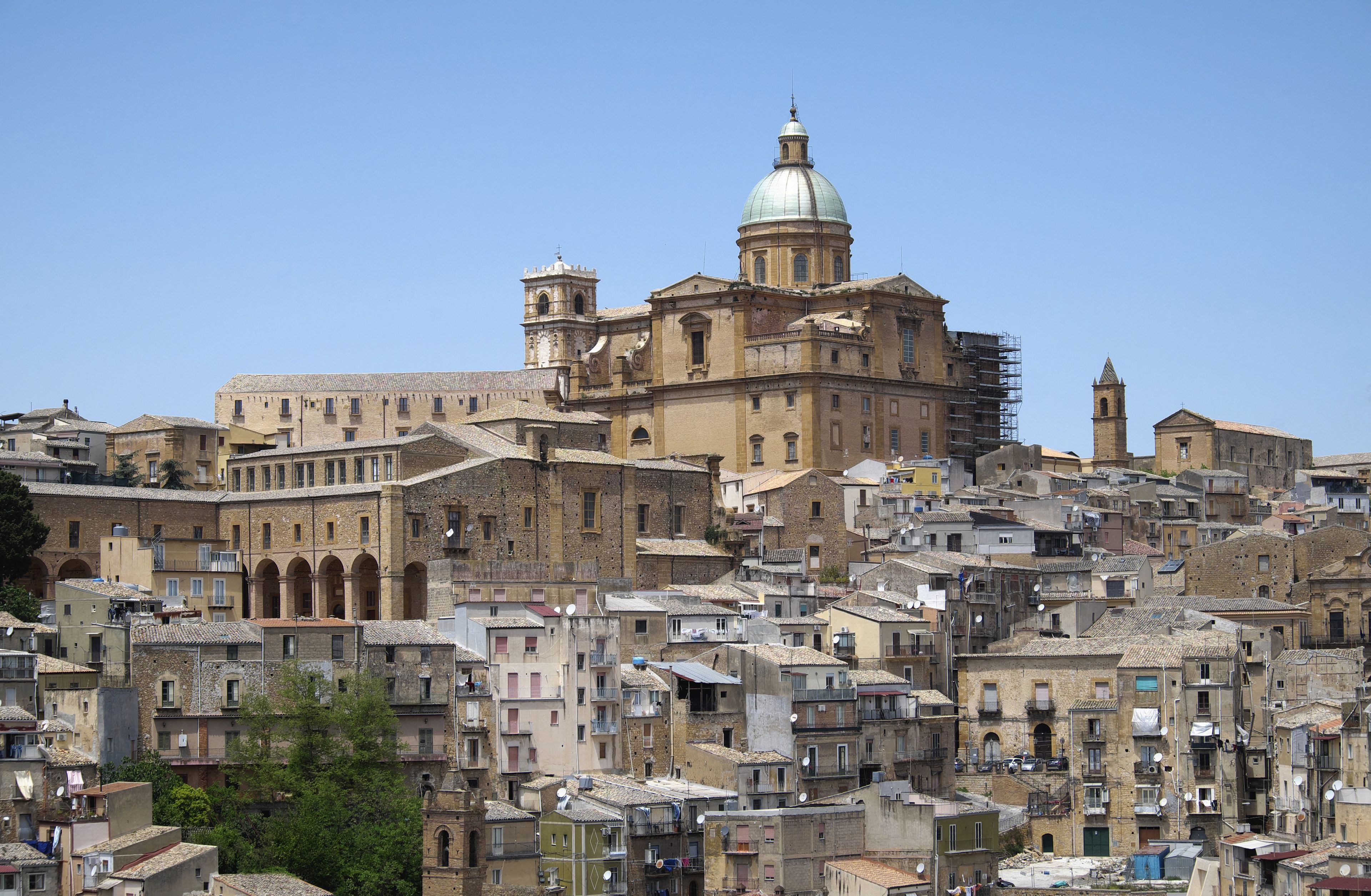 A historic cityscape with a prominent church featuring a dome and bell towers, surrounded by densely packed buildings.