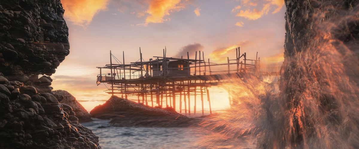 A pier extending into a body of water with a sunset in the background.