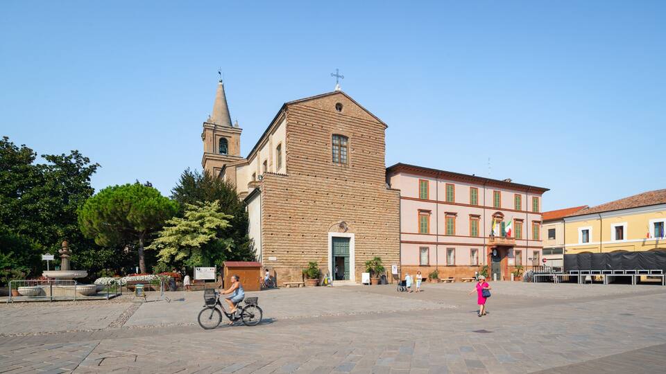 A historic church with a bell tower, a square plaza with people, and a fountain.