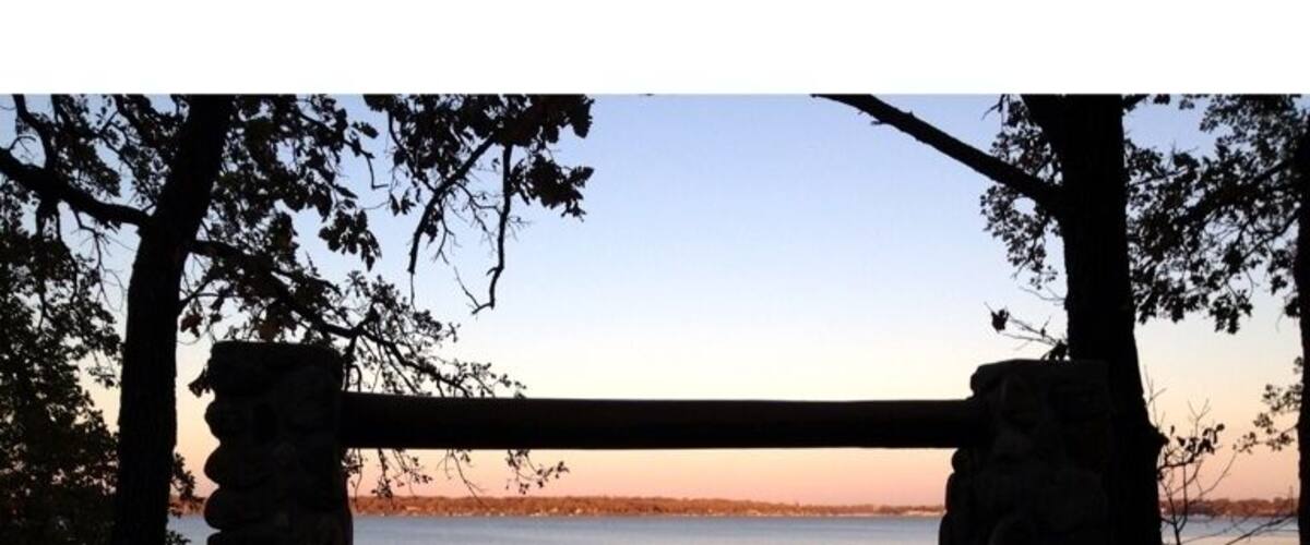 A stone bench overlooking a calm body of water during sunset.
