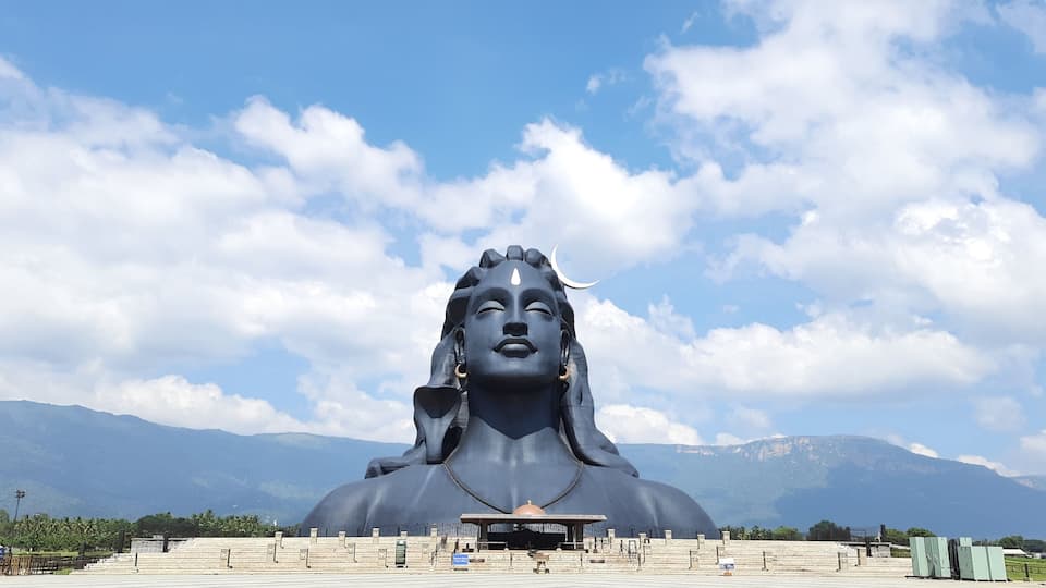 A large statue of a deity with mountains in the background.