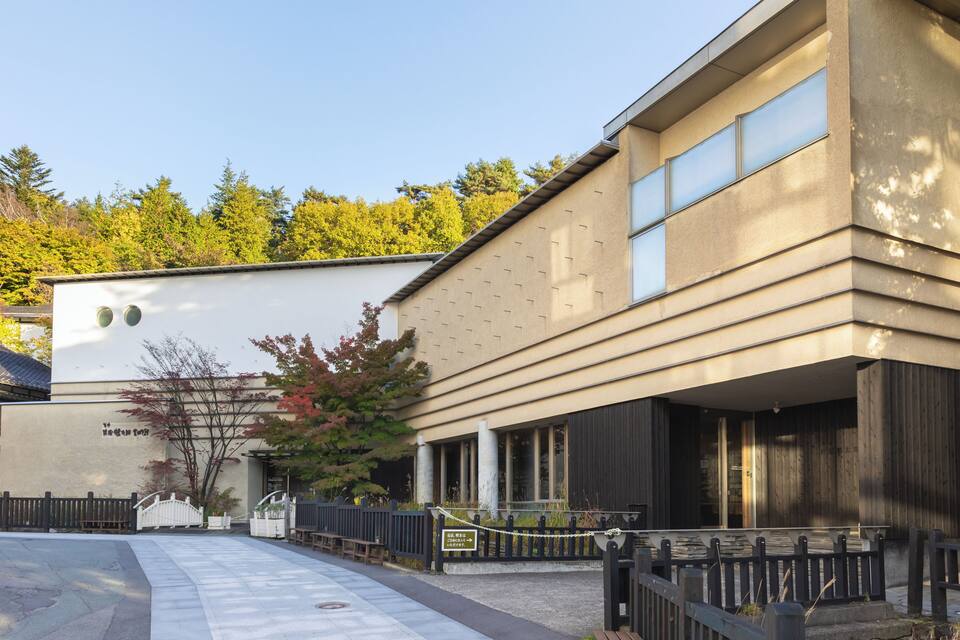 A modern building with a beige facade, large windows, and a gated entrance.