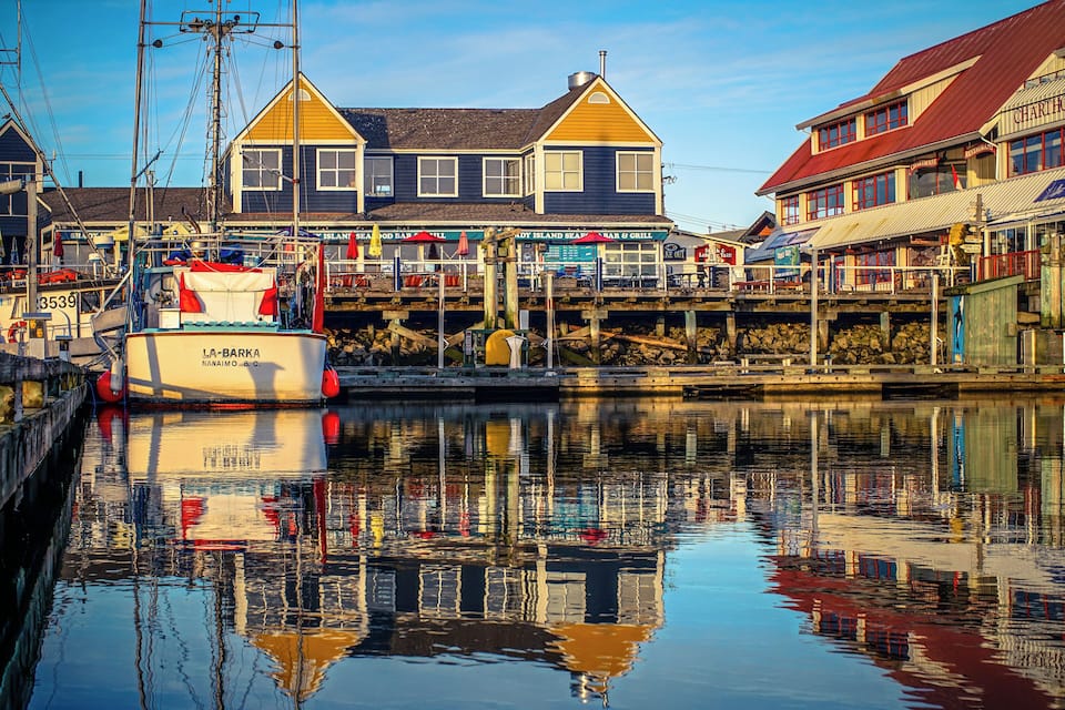 A waterfront with a boat named "La Barka" docked at a pier, surrounded by buildings with signs for "Island Sea Bar & Grill" and "Island Sea Restaurant."