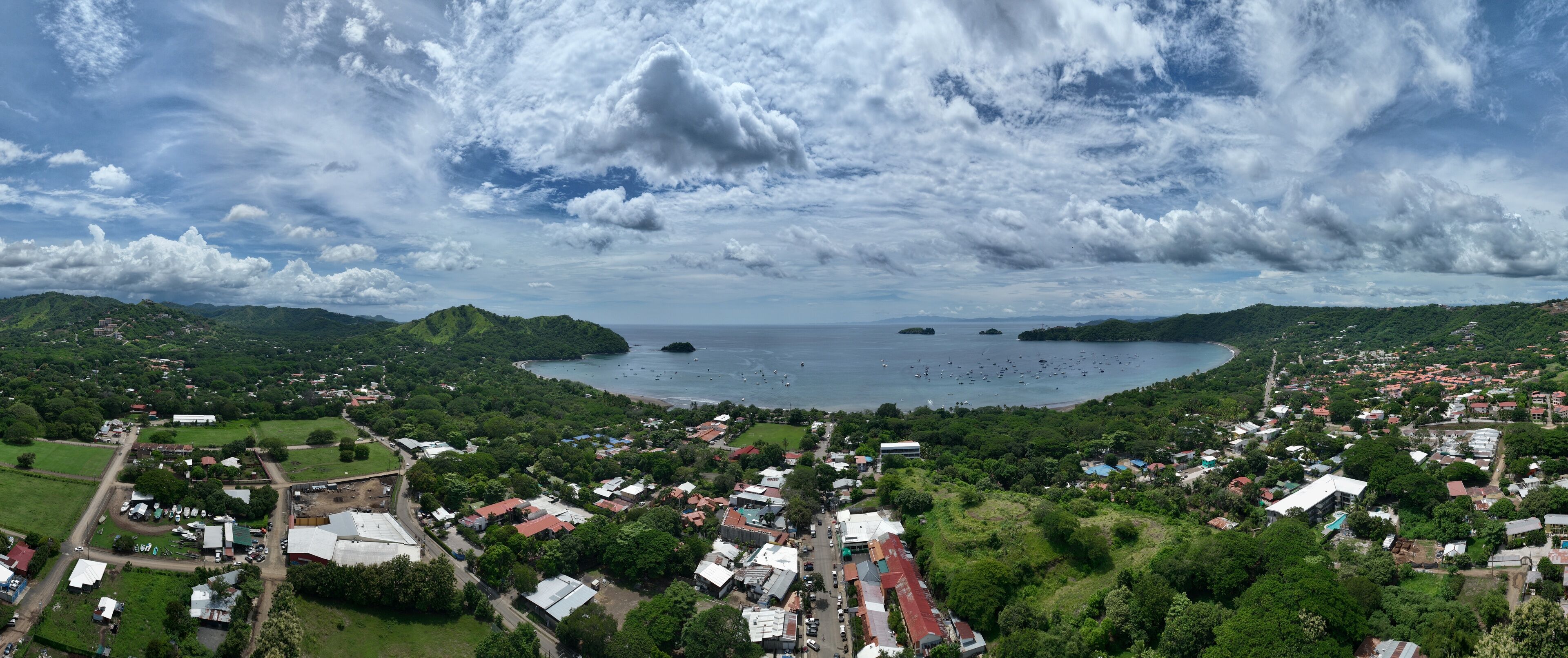 A coastal town with a bay, surrounded by hills and greenery.