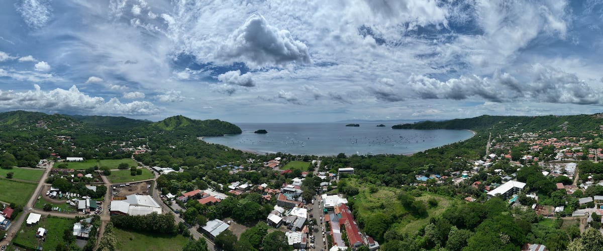A coastal town with a bay, surrounded by hills and greenery.