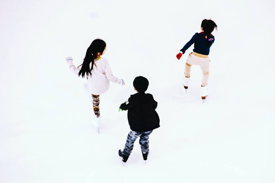 Three people ice skating on a white surface.