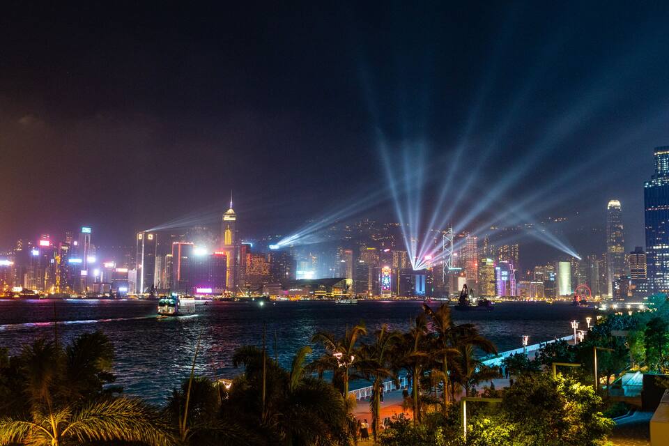 A nighttime cityscape with illuminated skyscrapers and a river.