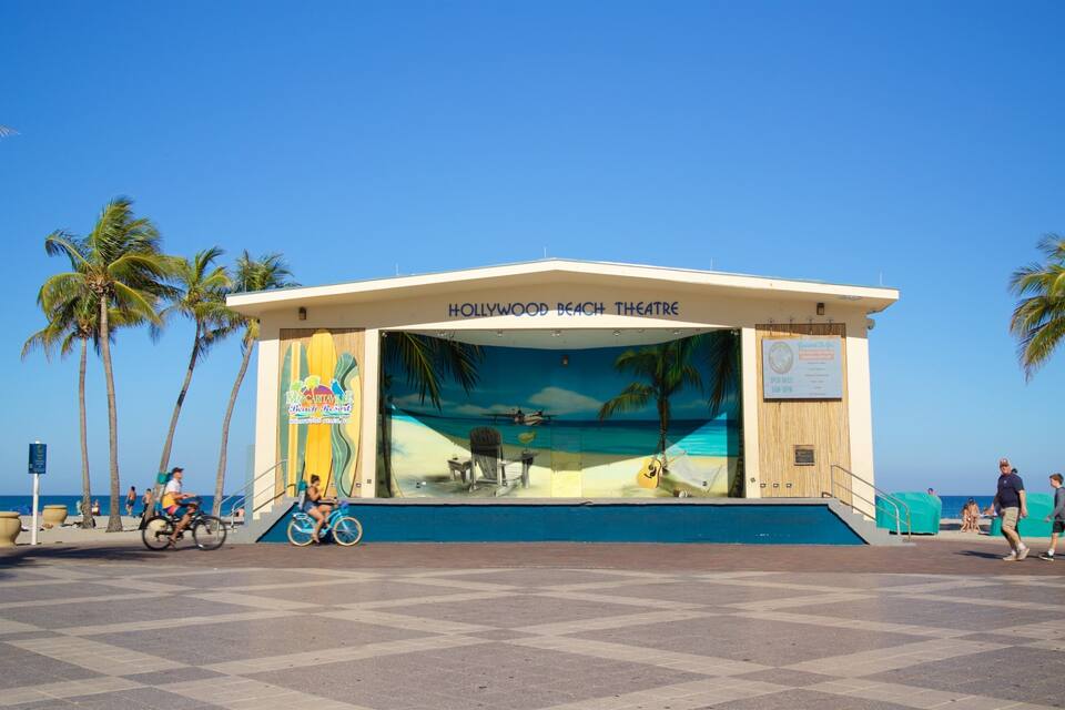 A beach theatre with palm trees and the ocean in the background.