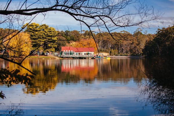 A lake with a house reflecting on the water, surrounded by trees and a clear sky.