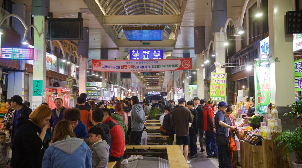 Seogwipo Maeil Olle Market showing night scenes and markets as well as a small group of people