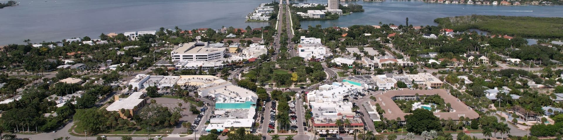 A coastal cityscape with a prominent bridge, dense urban development, and a marina.