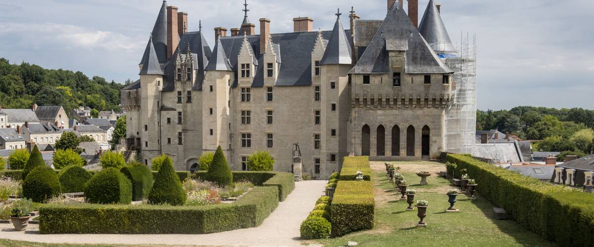 A historic castle with multiple towers and a well-maintained garden.