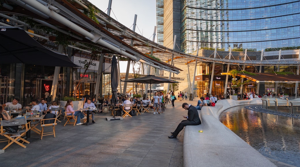 Piazza Gae Aulenti showing outdoor eating and a city as well as a small group of people