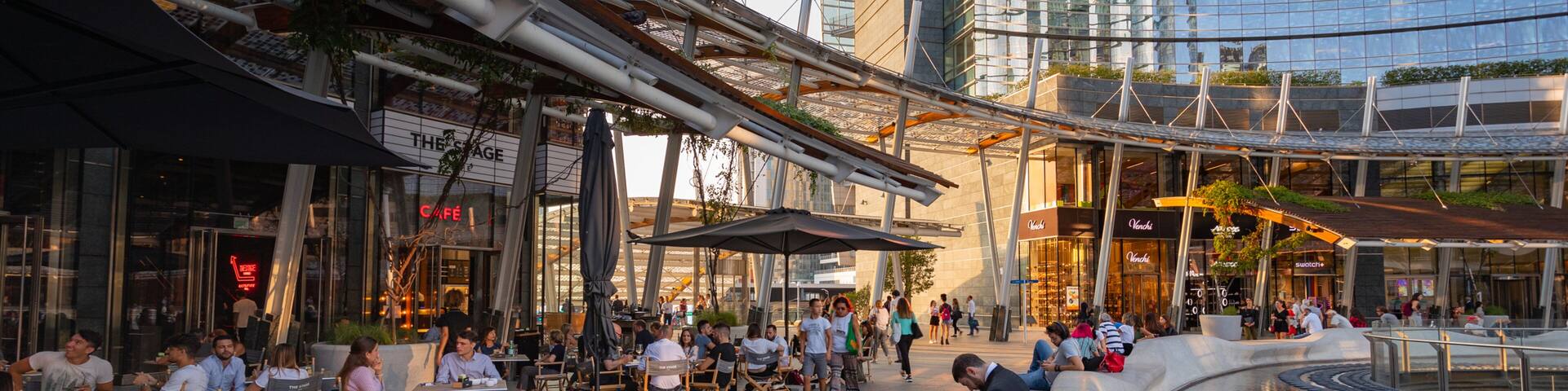 Piazza Gae Aulenti showing outdoor eating and a city as well as a small group of people