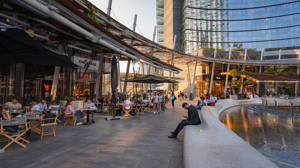 Piazza Gae Aulenti showing outdoor eating and a city as well as a small group of people