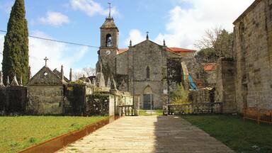 Una iglesia histórica con un campanario, rodeada de edificios de piedra y un estrecho sendero.