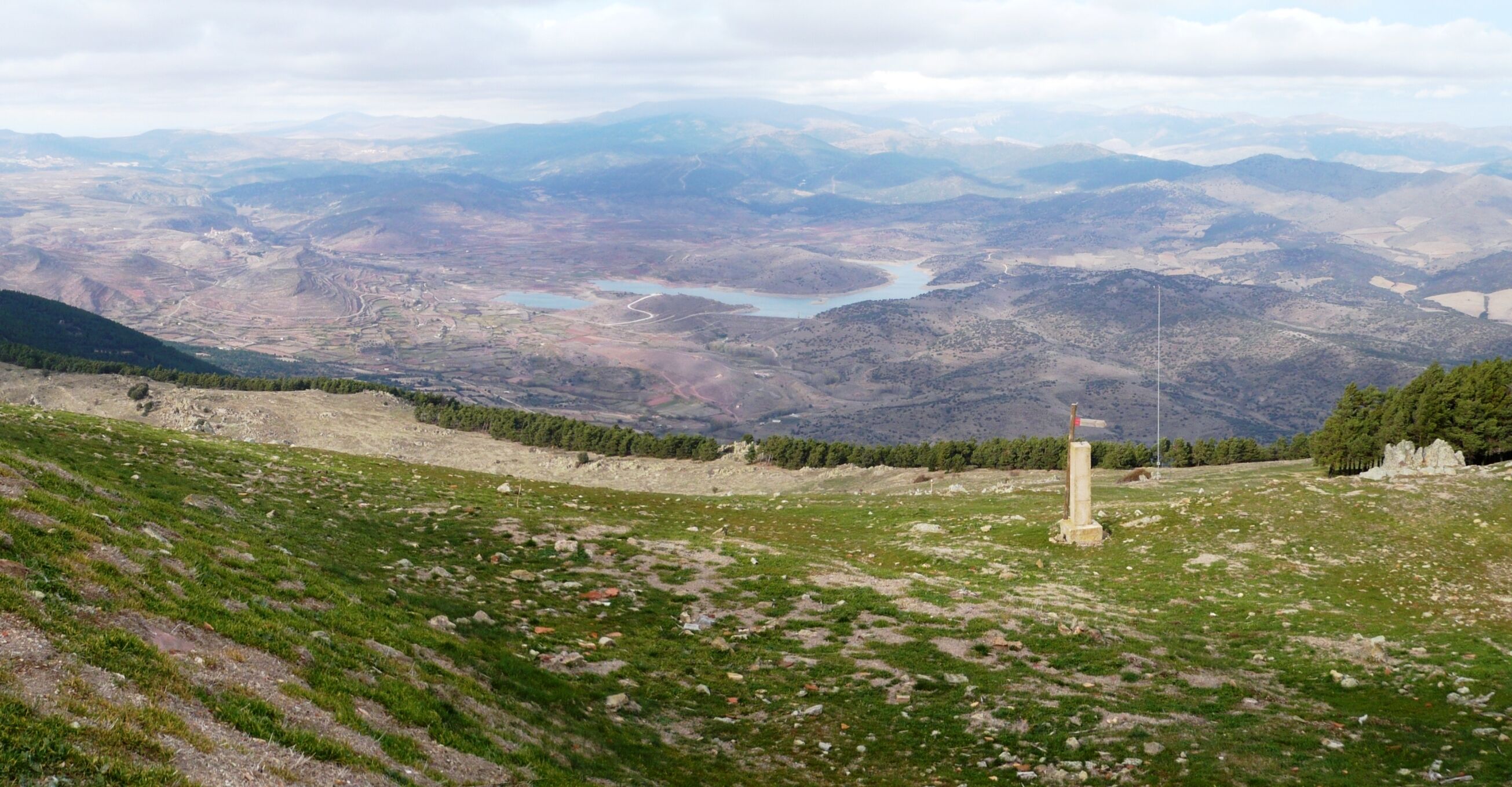 A mountainous landscape with a river, a monument, and distant mountains.