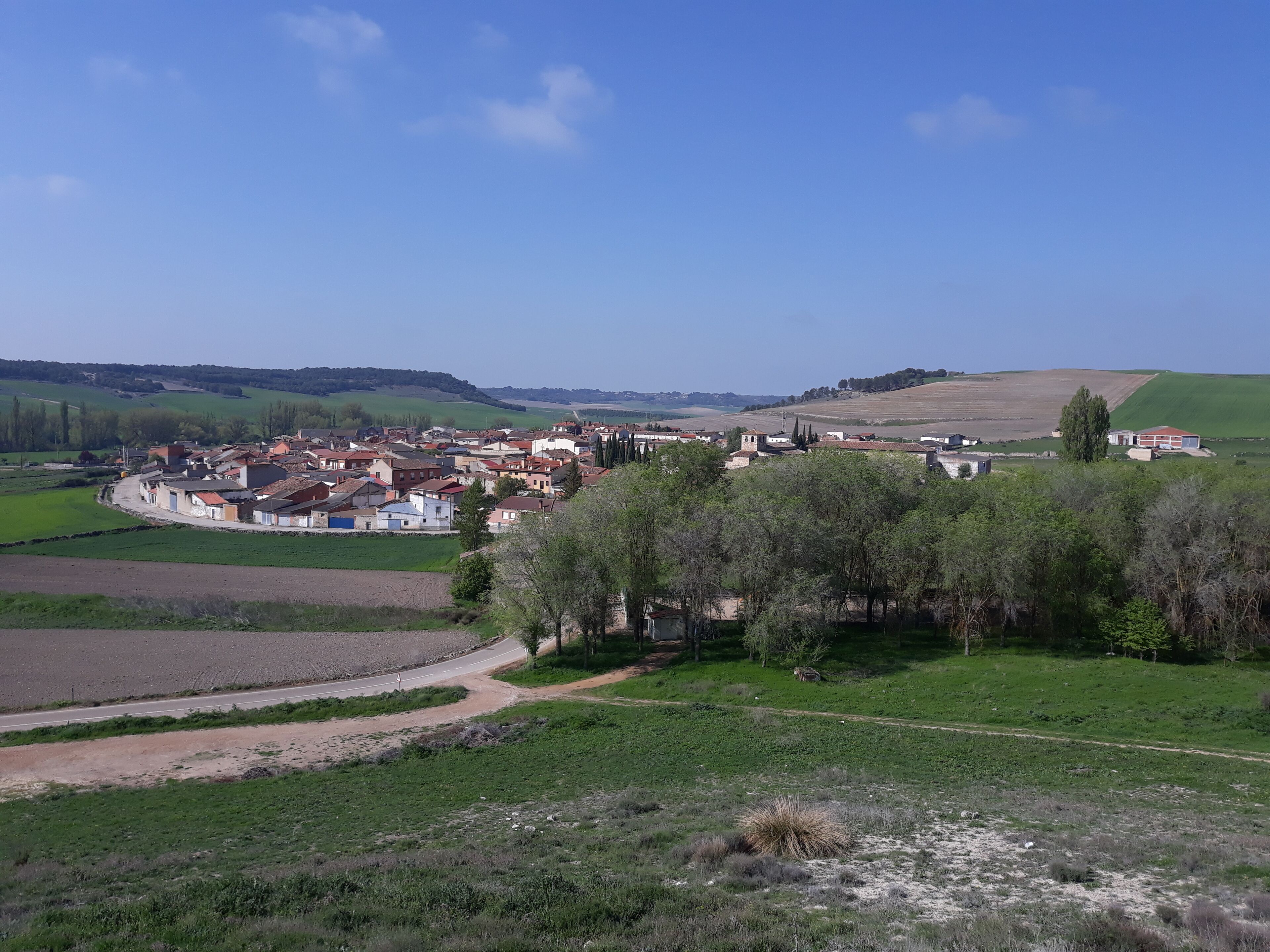 A rural village with houses, fields, and rolling hills in the background.