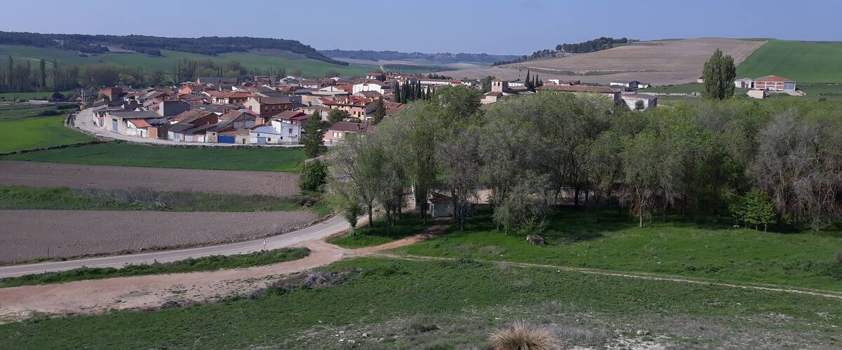 A rural village with houses, fields, and rolling hills in the background.