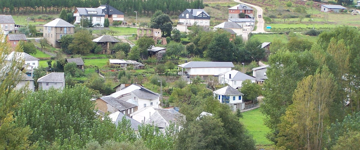 A rural village with houses surrounded by greenery and fields.