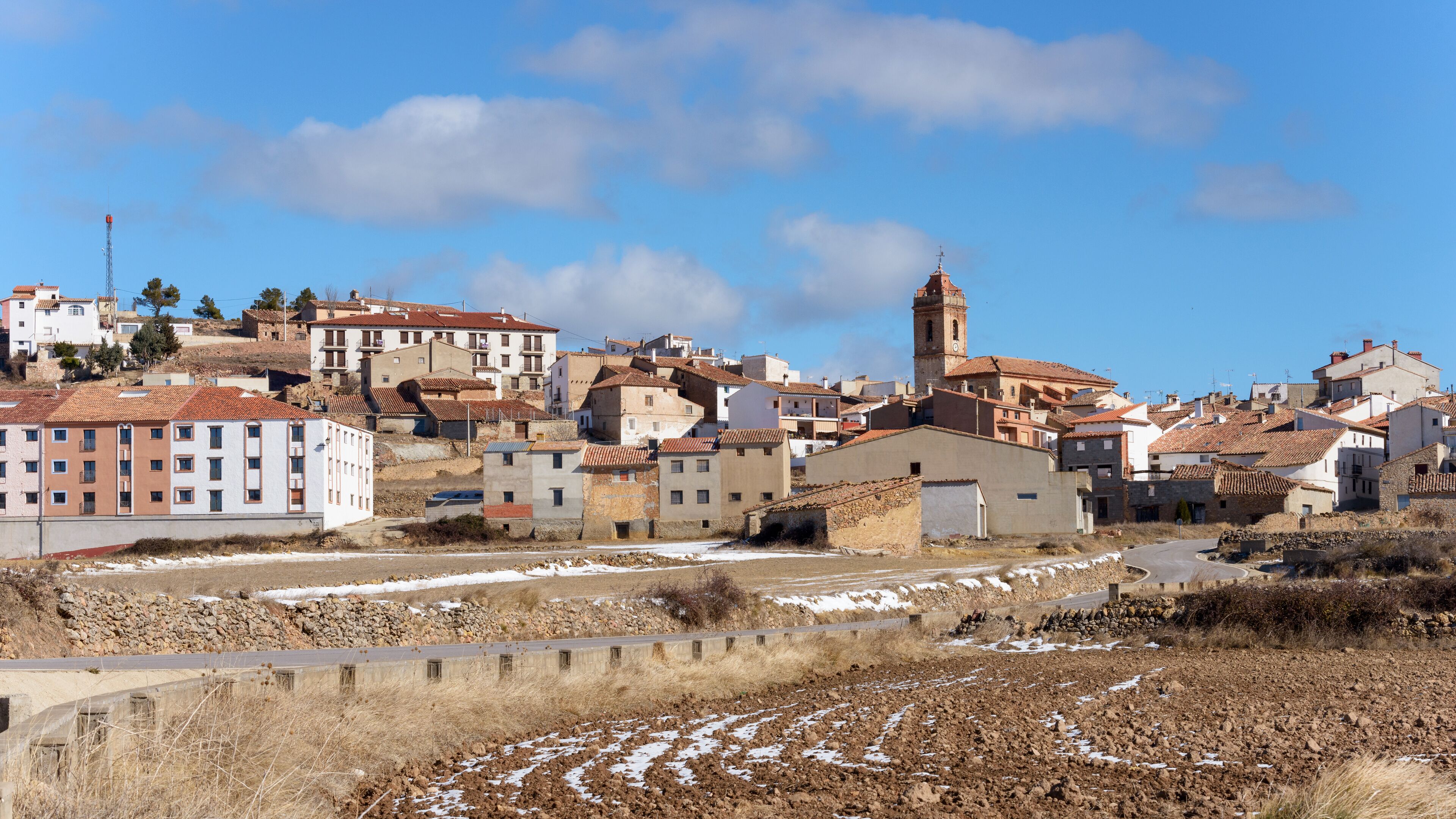 A town with a prominent church tower, terraced buildings, and a mix of modern and traditional architecture.