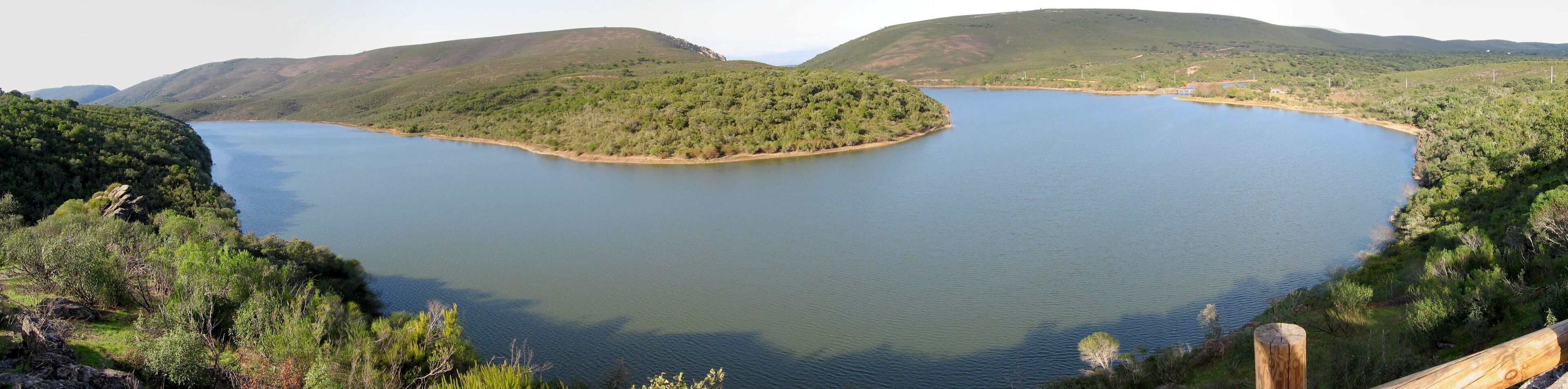 A lake surrounded by hills with dense greenery.