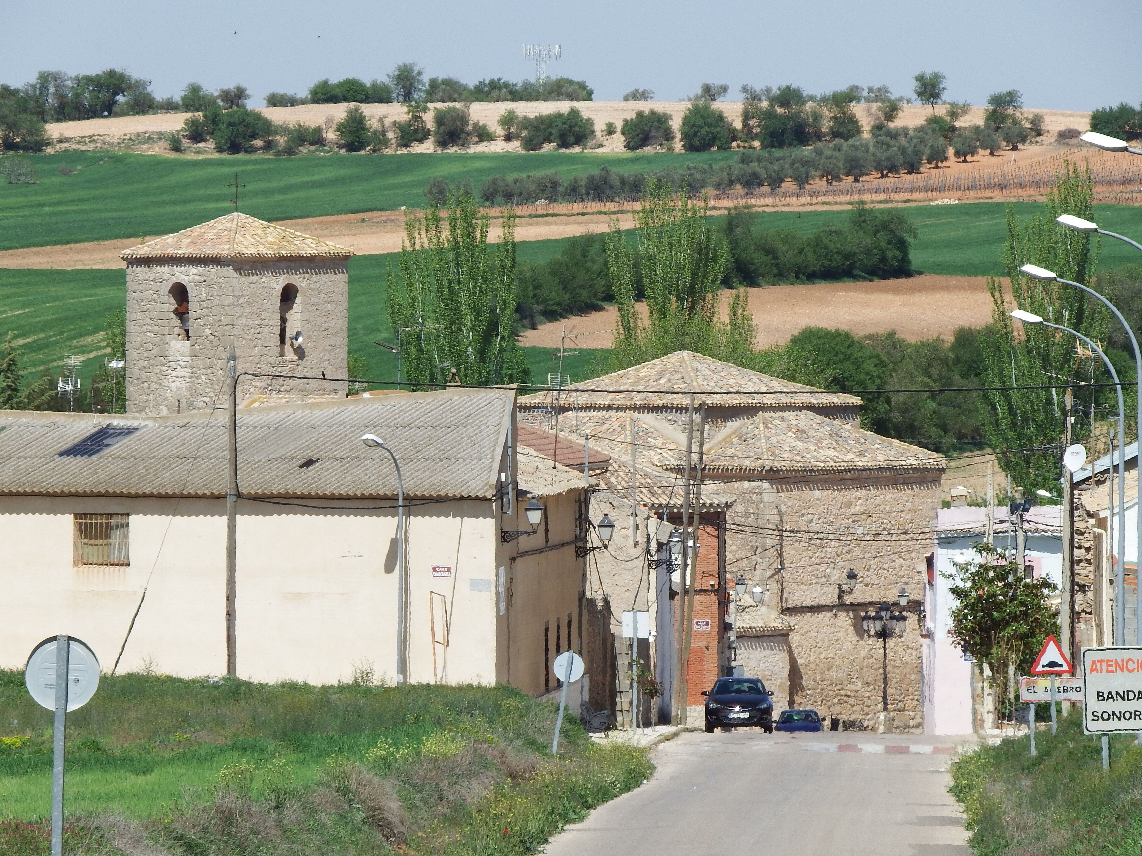 A rural village with stone buildings, a church, and green fields.