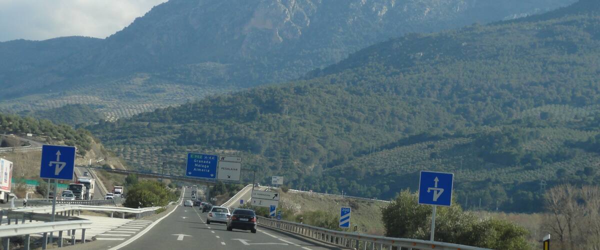 A highway with vehicles, road signs, and a mountainous landscape.
