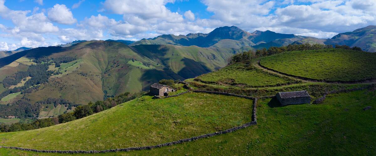 A green valley with stone walls and a stone house.